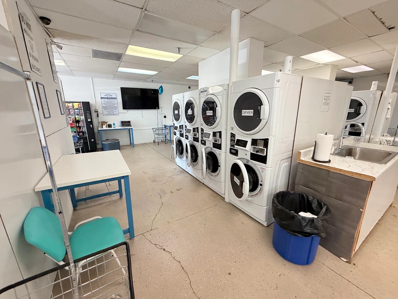 White stack dryers with folding tables and sink inside The Wash House Laughlin.